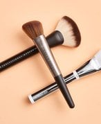 three makeup brushes on a colored background