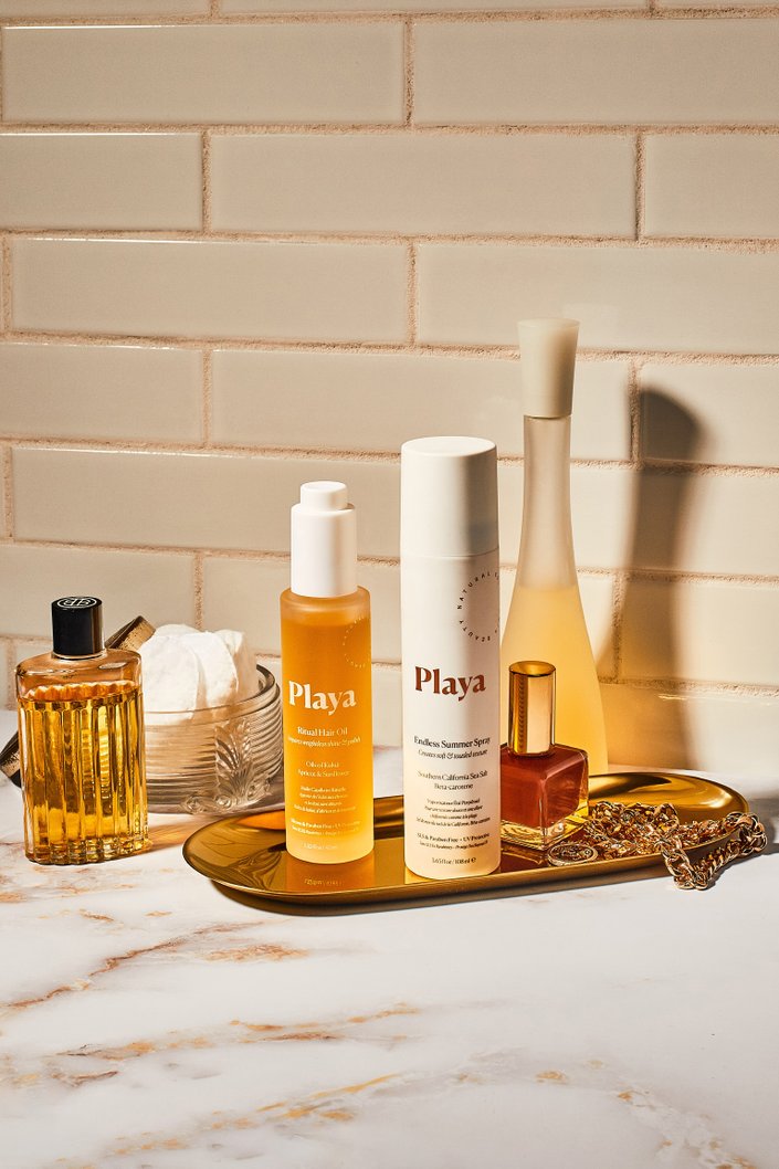 beauty products atop bronze tray on marble counter