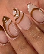 Close-up image of a hand with long brown and nude manicured Gel-x nails