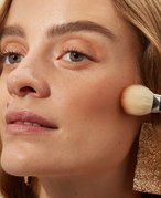 Person applying bronzer to their cheekbones