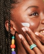 person applying sunscreen to cheek