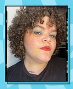 A person with curly hair wearing blue eyeshadow