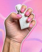 Photo of a hand with nails painted pink holding up the Essie Gel Couture Top Coat, against a pink and purple graphic background