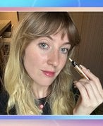 Picture of the editor holding the YSL Beauty Touche Éclat All-Over Brightening Pen on a graphic, multicolored background