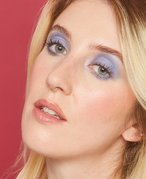 Picture of a person with blue eyes and blue eyeshadow on a red background