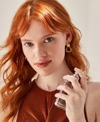 Picture of a red-haired model spraying perfume on their neck