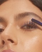 Close-up of a person applying blue mascara to their eyelashes